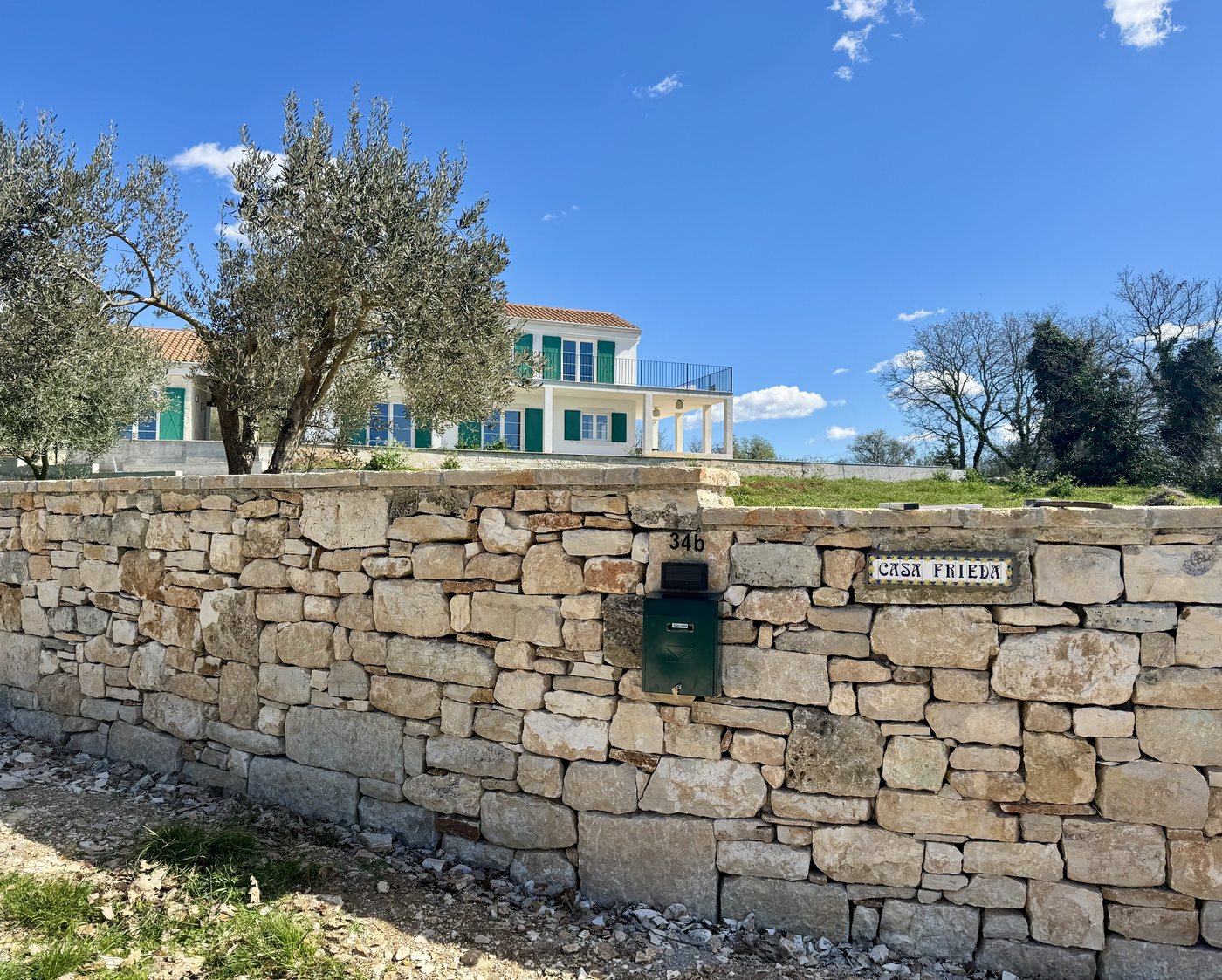 The house above the dry stone wall, with the Casa Frieda sign