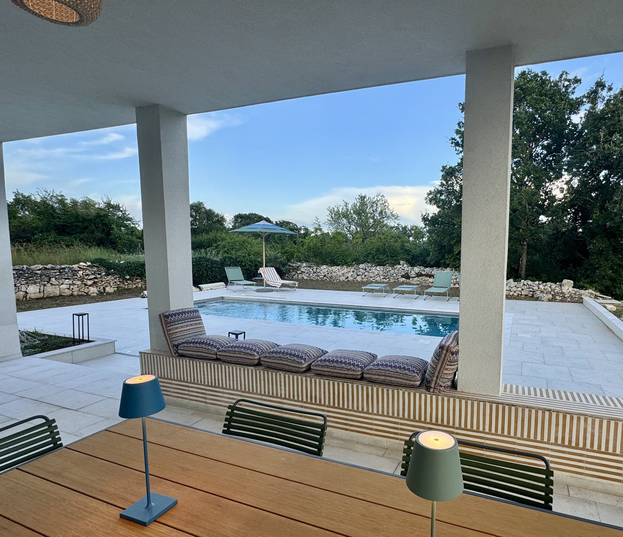 The view from under the loggia at Casa Frieda, across the cushioned bench to the pool