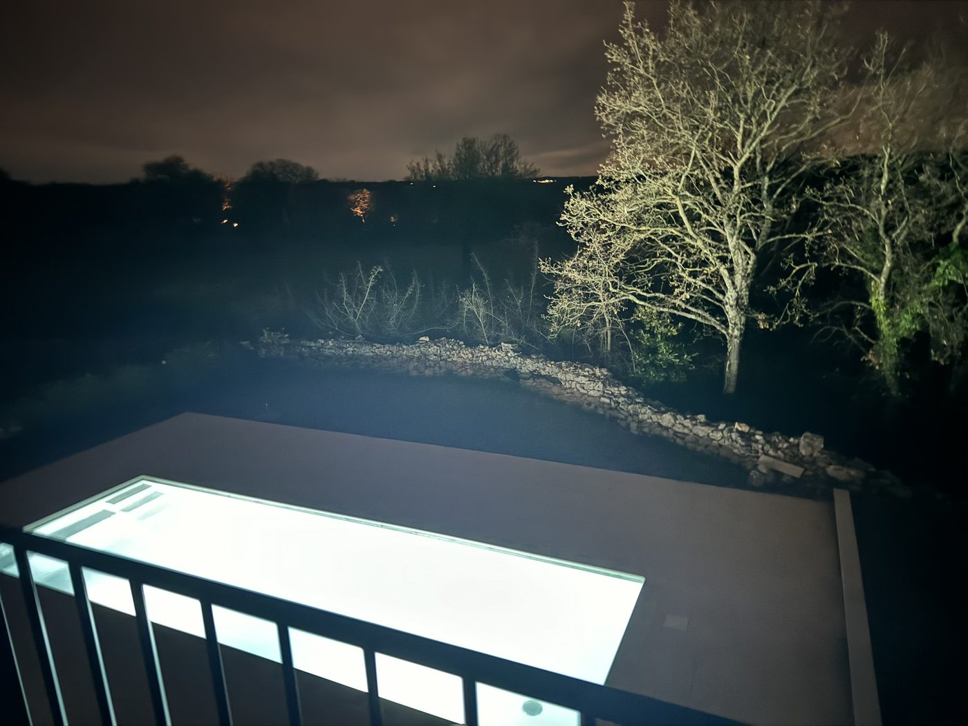 The lit pool at night, seen from the terrace above