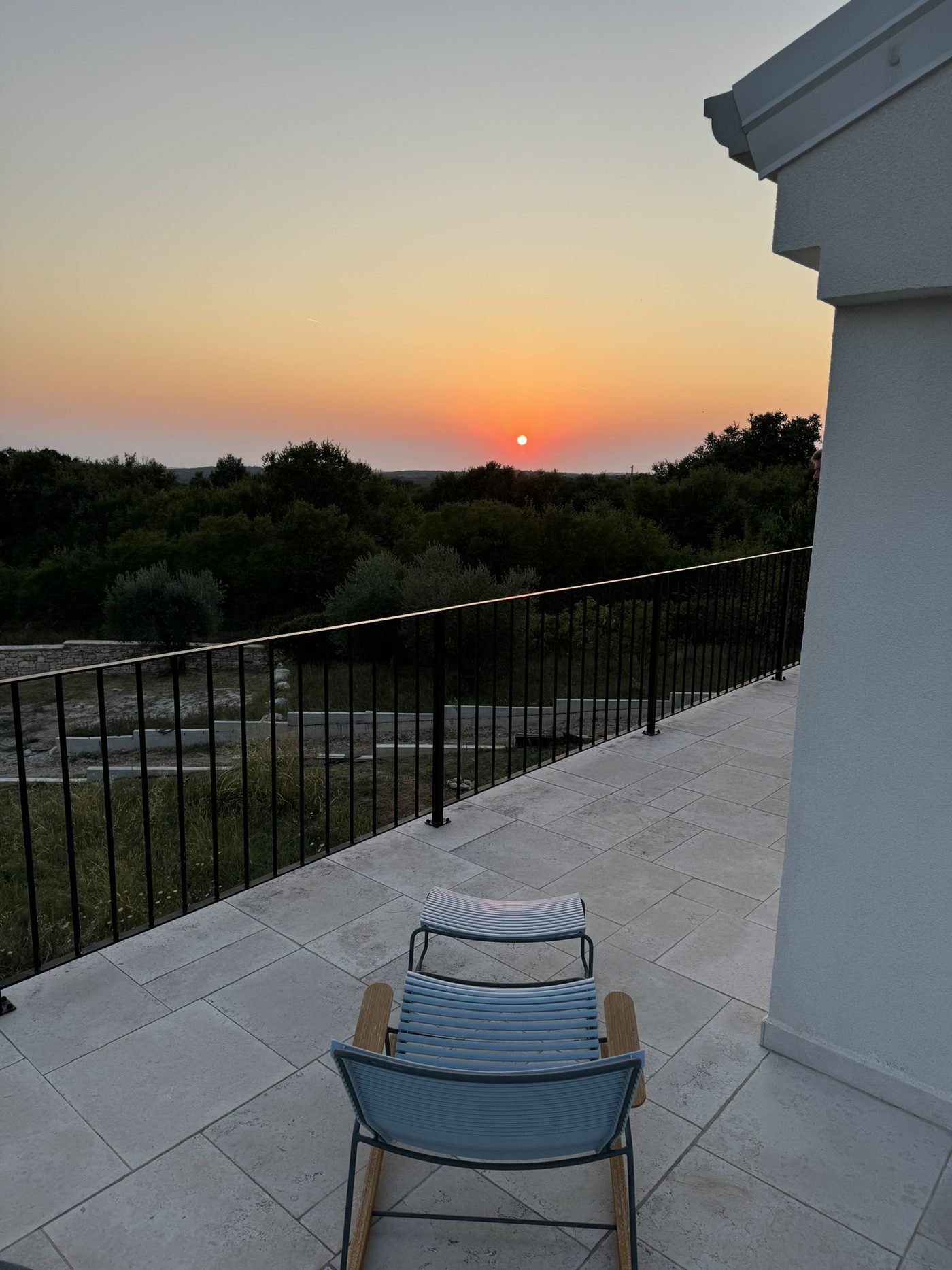 A chair on the upper terrace facing the sunset